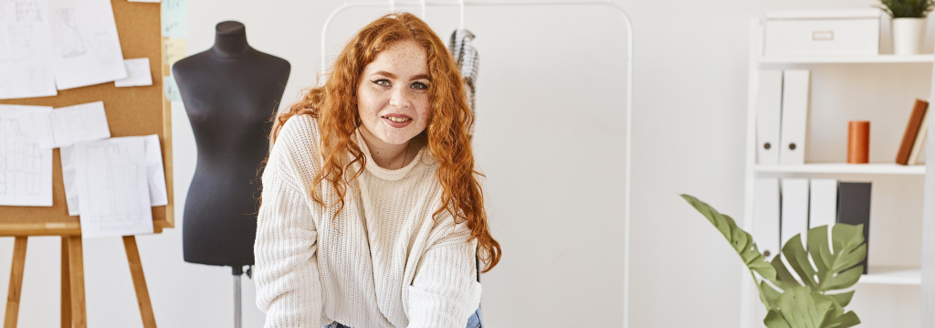 front-view-smiley-female-fashion-designer-working-atelier-with-laptop.jpg